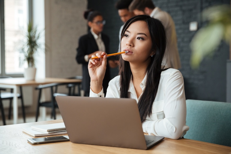 Thoughtful young asian business woman woman pondering location of ghost assets at her laptop
