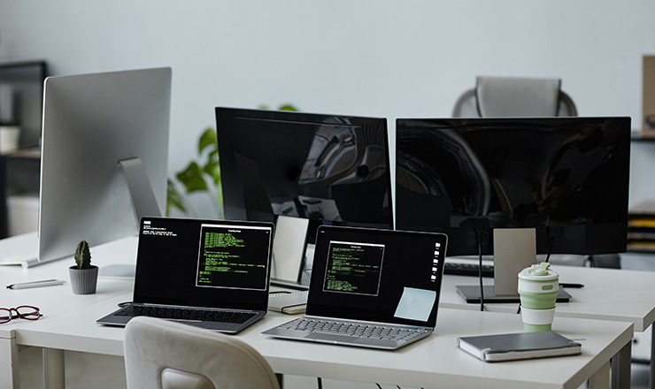 Workplace with IT equipment including laptops and monitors on a table