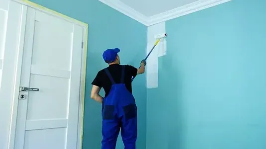 Painter rolling paint onto a wall