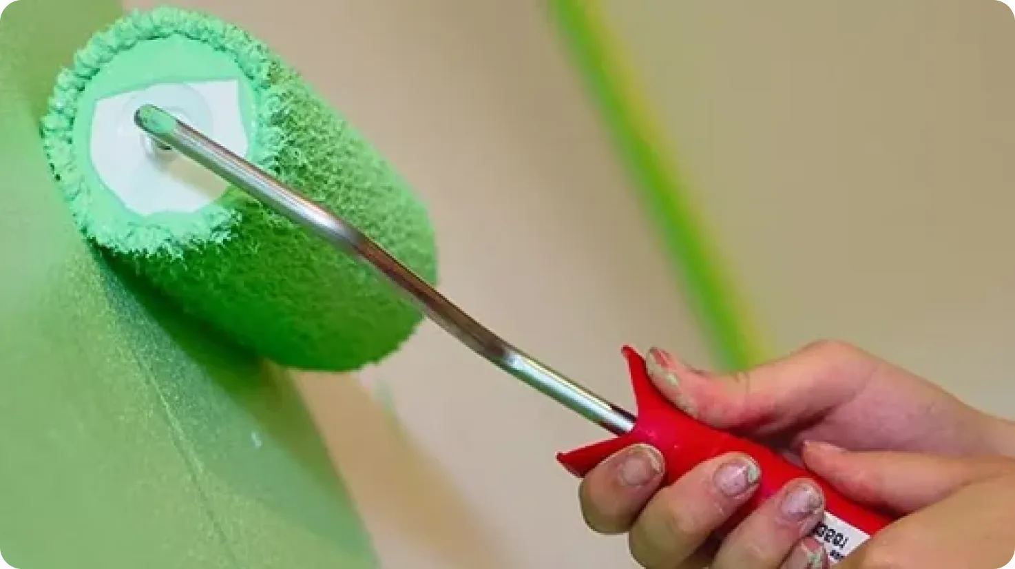 Paint roller applying green paint to a wall